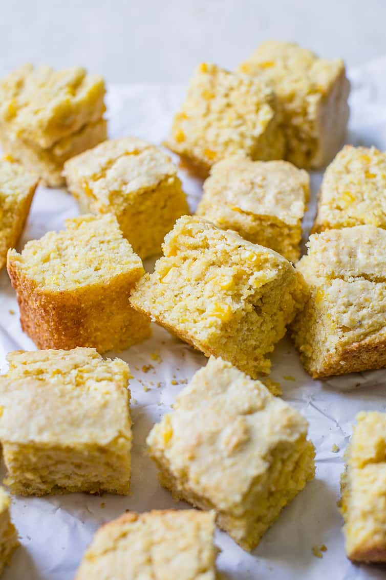 Squares of cornbread on a piece of parchment paper.