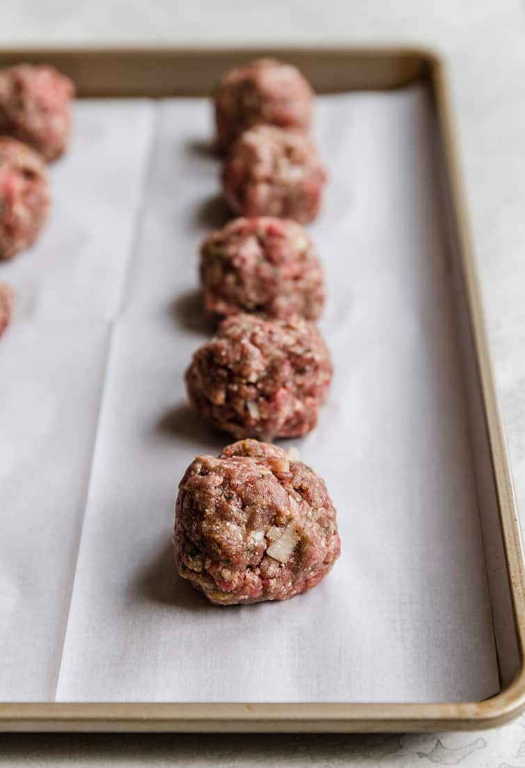Shaped meatballs on a baking sheet prior to baking.