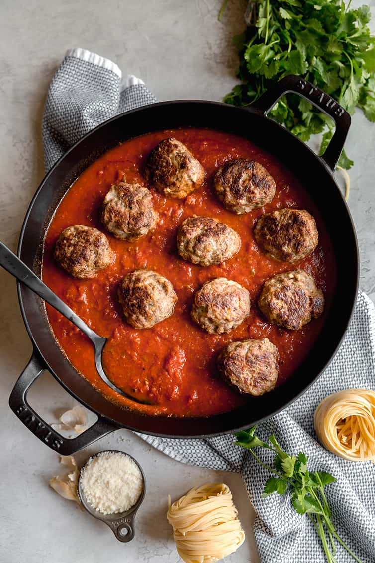 Meatballs added to a pot of sauce.