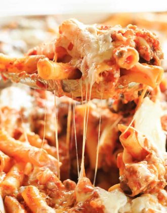 A spoonful of baked ziti being scooped out the pan.