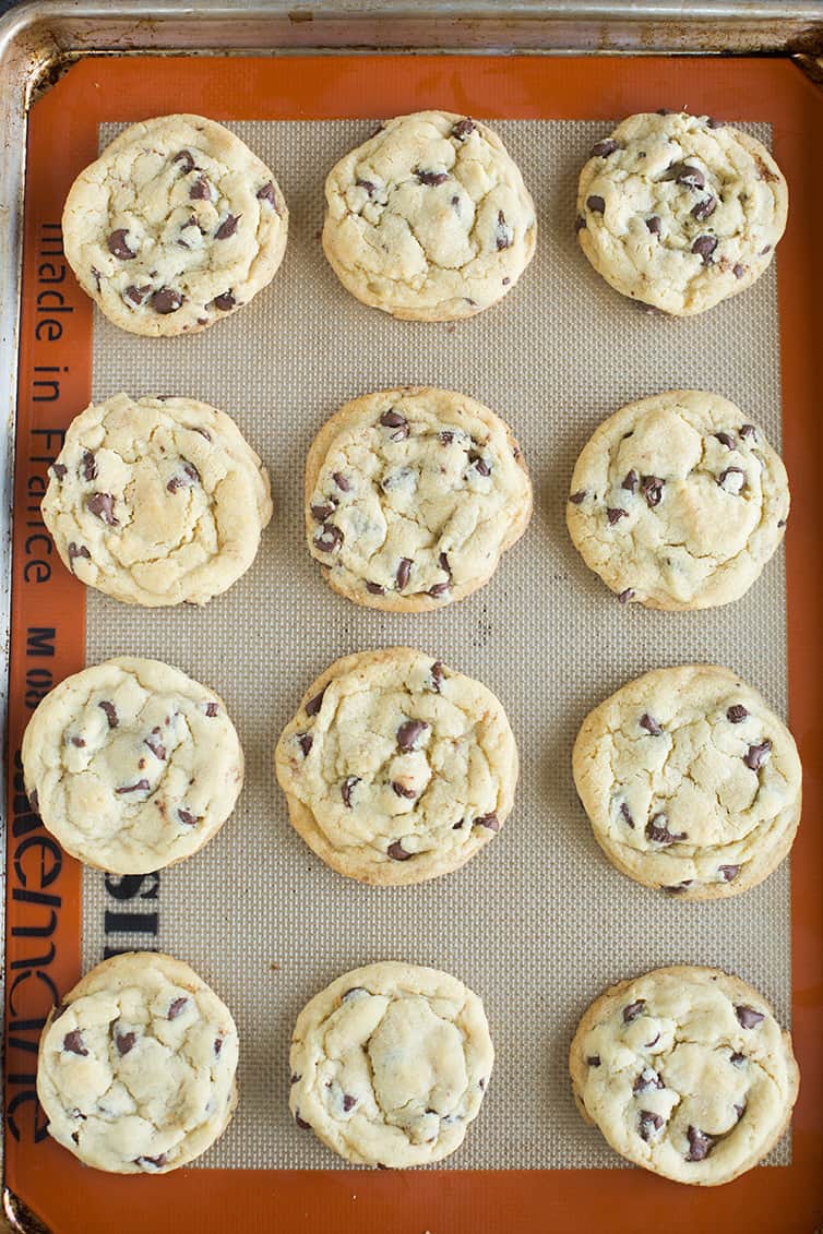 An overhead shot baked chocolate chip cookies on a baking sheet.