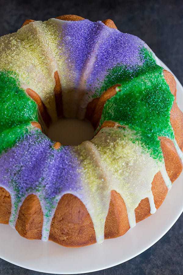 A festive King Cake for Mardi Gras - filled with a pecan, brown sugar and cinnamon swirl - baked into a Bundt pan and decorated with colored sanding sugars.
