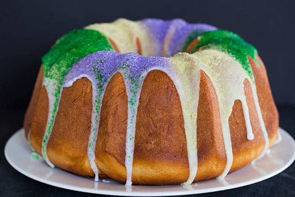 A festive King Cake for Mardi Gras - filled with a pecan, brown sugar and cinnamon swirl - baked into a Bundt pan and decorated with colored sanding sugars.