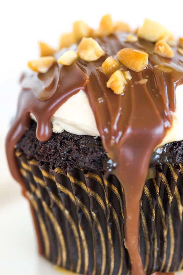 These Snickers cupcakes taste JUST like the candy bar... A chocolate cupcake filled with peanut nougat, topped with a caramel buttercream frosting, covered in a chocolate ganache, chopped peanuts and a drizzle of caramel sauce.