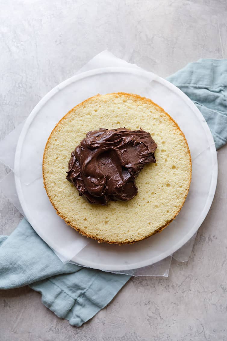 A layer of yellow cake with a dollop of chocolate frosting on top.