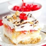 No Bake Banana Split Dessert is a classic! It layers a graham cracker crust, cream cheese-based filling, bananas, pineapple, strawberries, whipped cream, nuts, chocolate & a cherry on top!