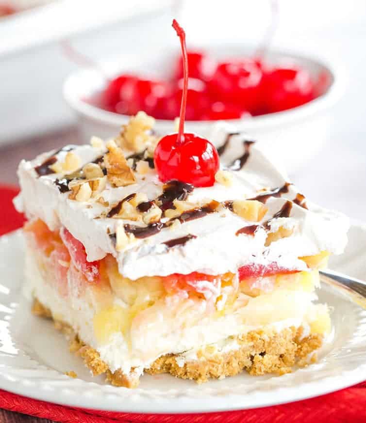 No Bake Banana Split Dessert is a classic! It layers a graham cracker crust, cream cheese-based filling, bananas, pineapple, strawberries, whipped cream, nuts, chocolate & a cherry on top!