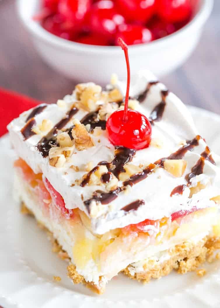 No Bake Banana Split Dessert is a classic! It layers a graham cracker crust, cream cheese-based filling, bananas, pineapple, strawberries, whipped cream, nuts, chocolate & a cherry on top!