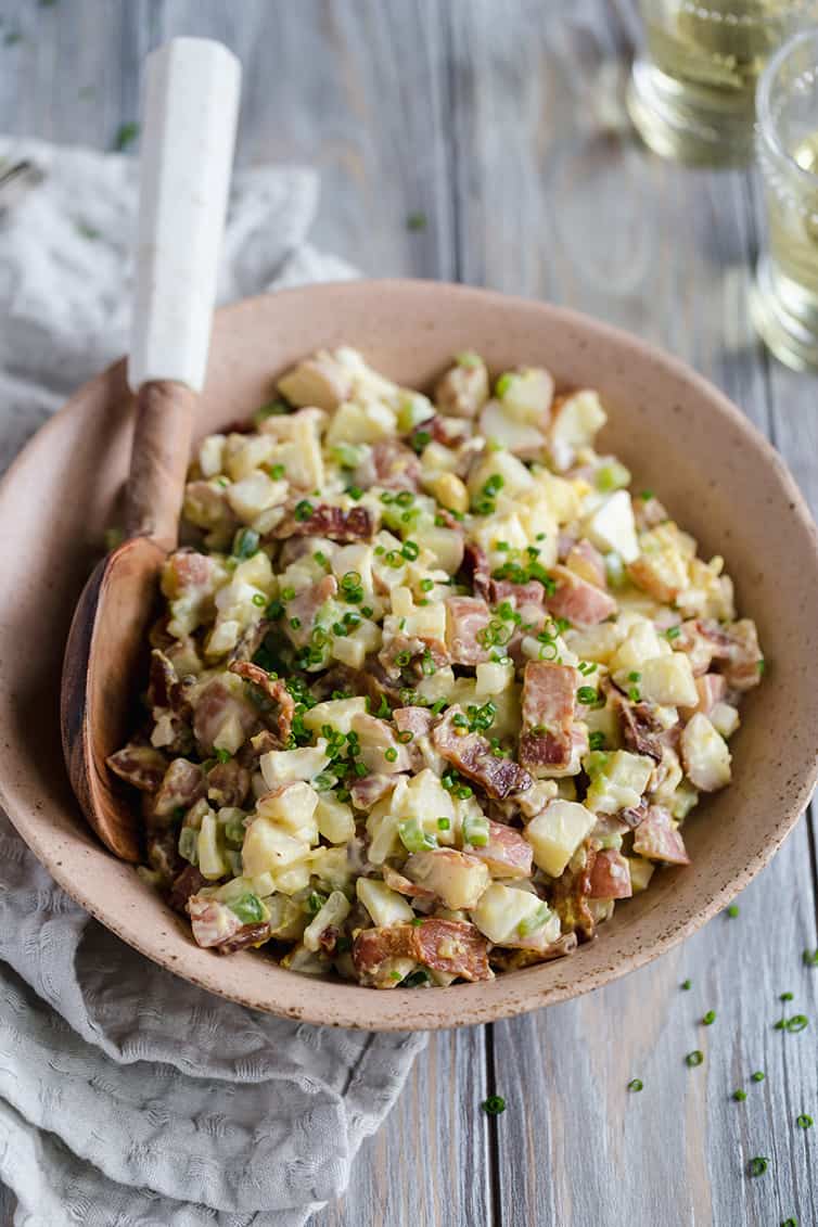 A bowl of potato salad with a serving spoon.