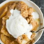 A plate of apple crisp with a scoop of ice cream on top.