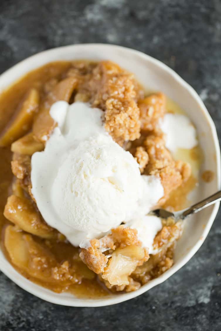 A plate of apple crisp with a scoop of ice cream on top.