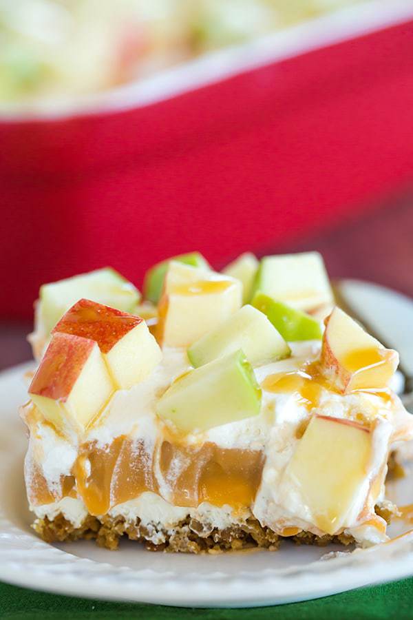 This caramel apple pudding has layers of caramel cheesecake filling, caramel pudding, a whipped cream topping, apples, and peanuts all on top of a gingersnap crust.