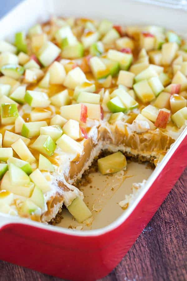 This caramel apple pudding has layers of caramel cheesecake filling, caramel pudding, a whipped cream topping, apples, and peanuts all on top of a gingersnap crust.