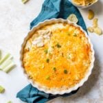 A pan of cheesy buffalo chicken dip with celery and chips for dipping.