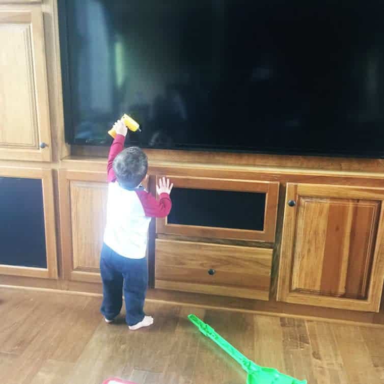 Joseph trying to fix the TV with his toy drill.