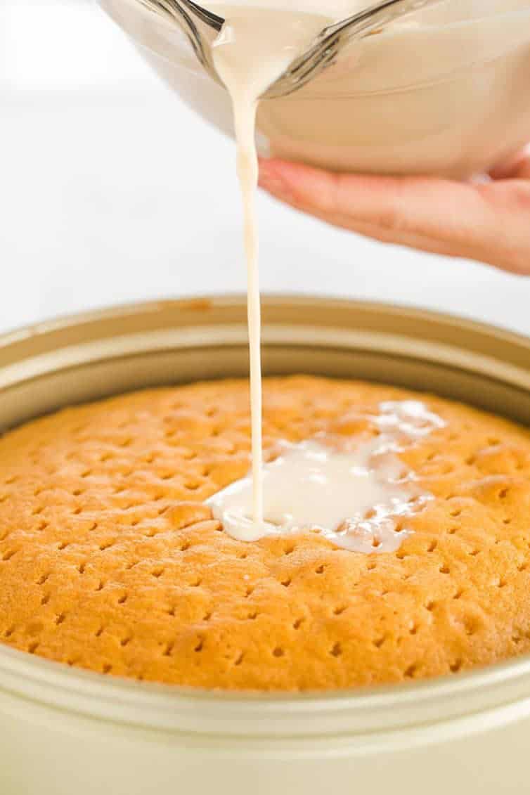 Pouring the three-milk mixture all over the caramel tres leches cake.