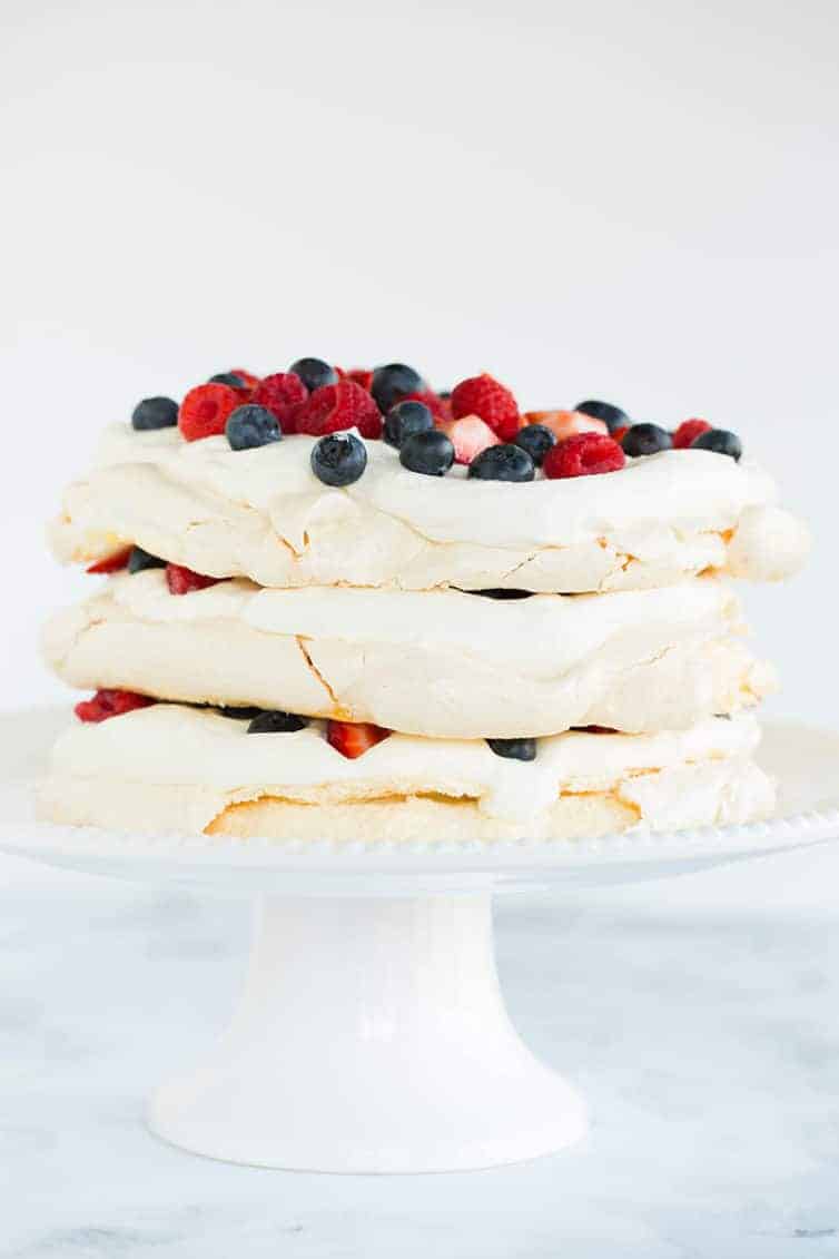 Three layers of pavlova filled and topped with whipped cream and berries.