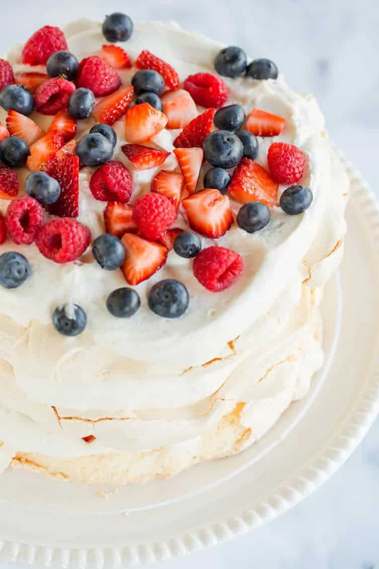An overhead view of a pavlova layer cake with whipped cream and berries.