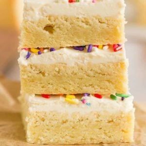 A stack of three sugar cookie bars with frosting and sprinkles.