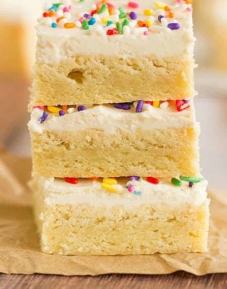 A stack of three sugar cookie bars with frosting and sprinkles.