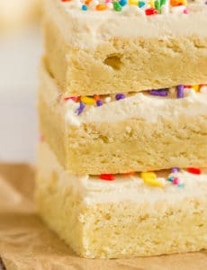 A close-up shot of a stack of frosted sugar cookie bars.