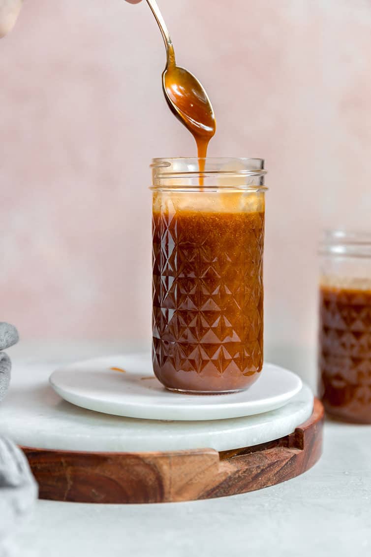 A jar of salted caramel sauce with a spoon scooping some out.