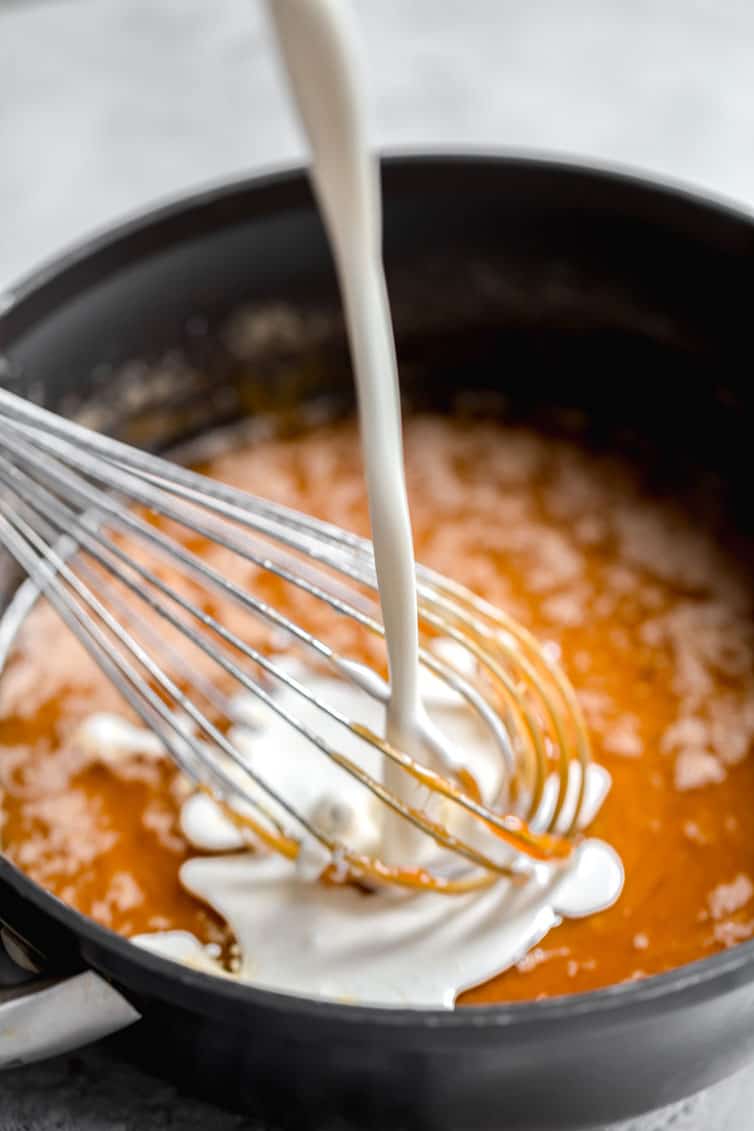 Cream being whisked into a caramel sauce.