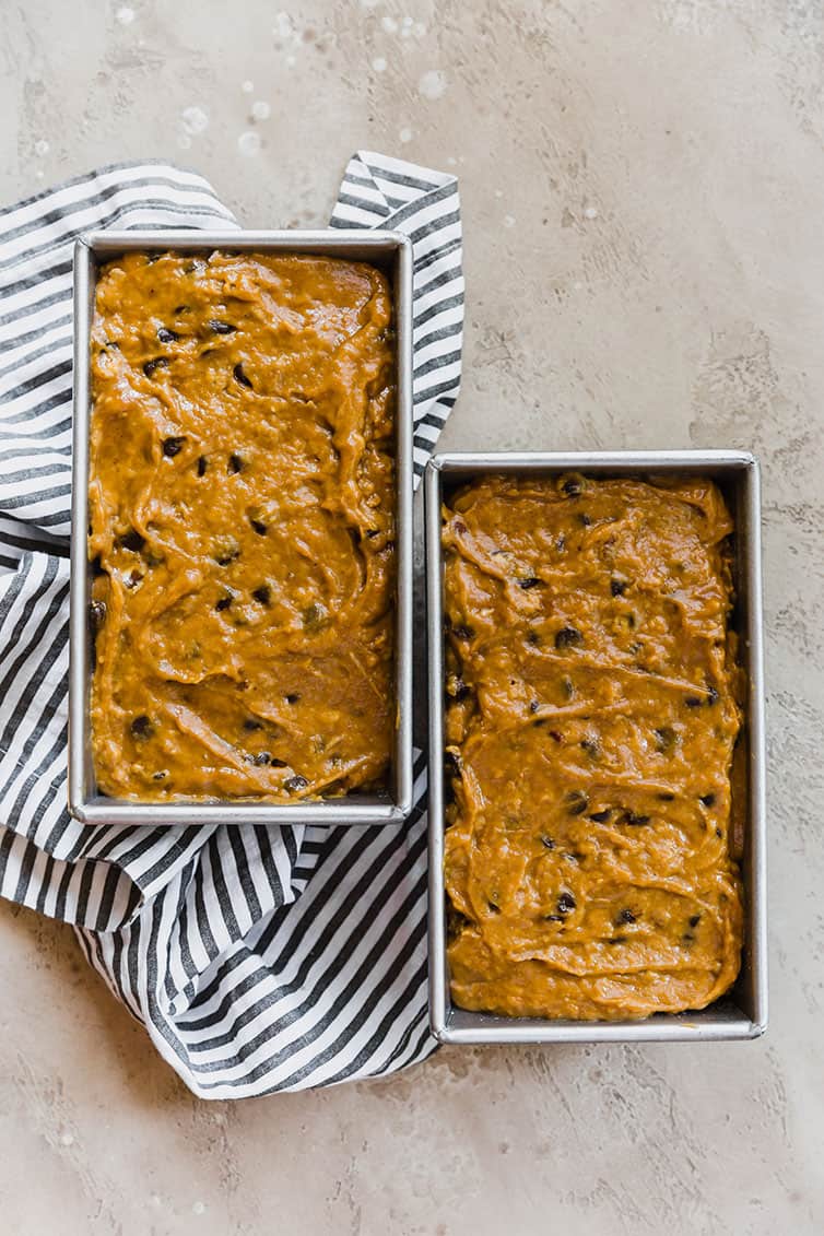 Two loaf pans filled with pumpkin bread batter.
