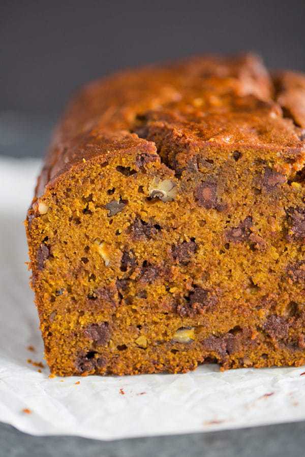A cut loaf of pumpkin bread with chocolate chips and pecans.