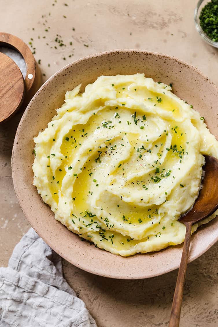 Mashed potatoes in a serving bowl with a wooden spoon.