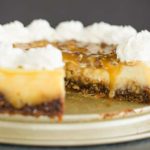 A whole pecan pie cheesecake with a slice removed.