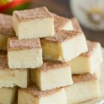 Squares of snickerdoodle fudge stacked on a white plate.
