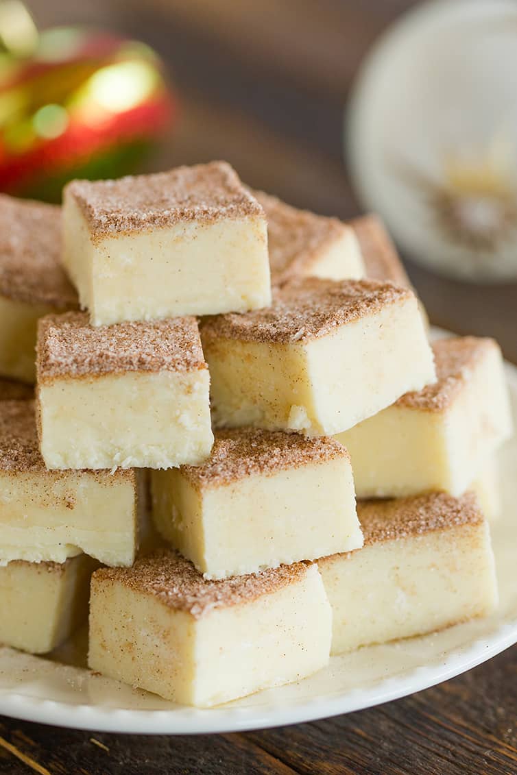 Squares of snickerdoodle fudge stacked on a white plate.