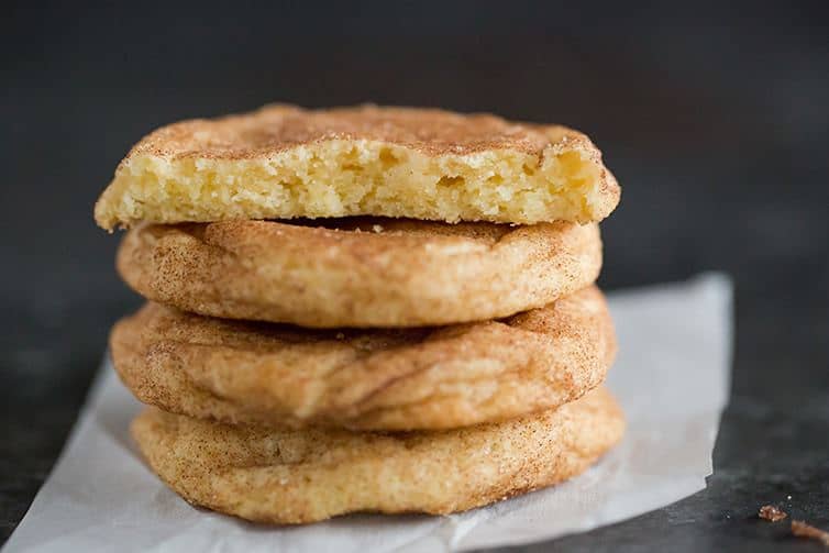 A stack of four snickerdoodle cookies with the top one broken in half.