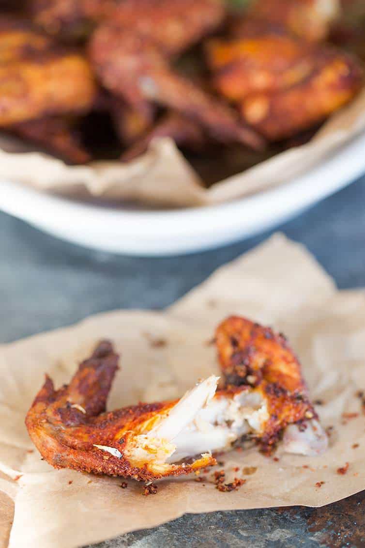 A cooked chicken wing on a piece of butcher paper.