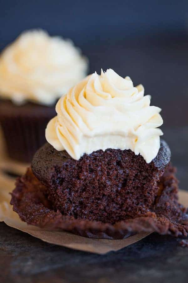 A chocolate cupcake with vanilla frosting with a bite taken out.