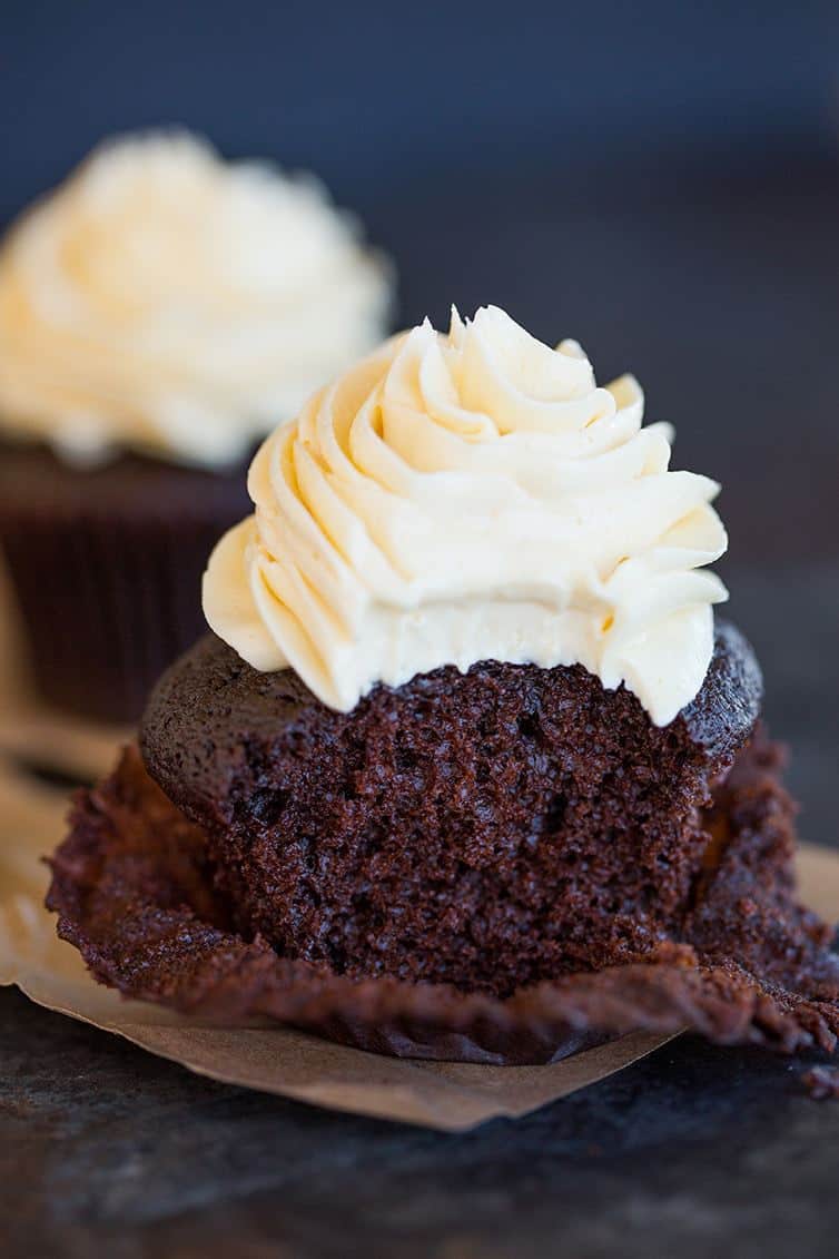 A chocolate cupcake with vanilla frosting with a bite taken out.