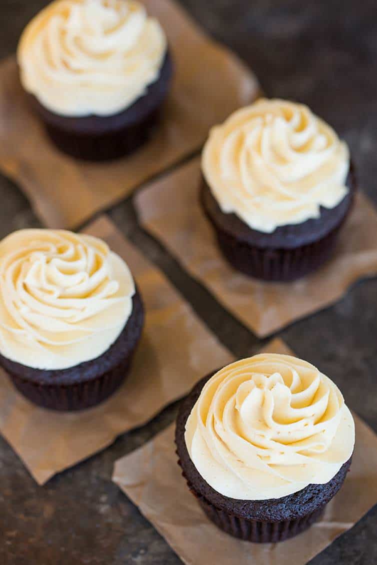 An overhead shot of four chocolate cupcakes with vanilla frosting.