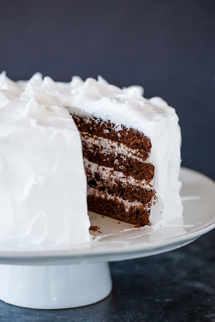 Devil's food cake on a cake stand with a slice of cake removed.