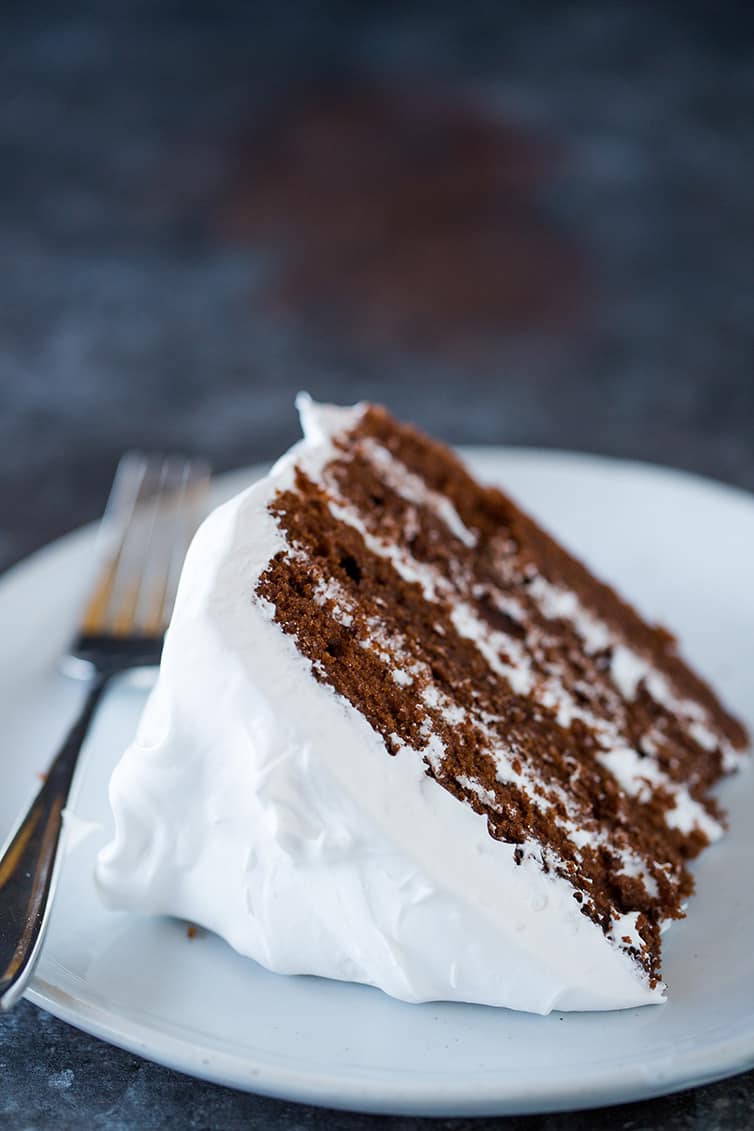A slice of four-layer devil's food cake on a plate with a fork.