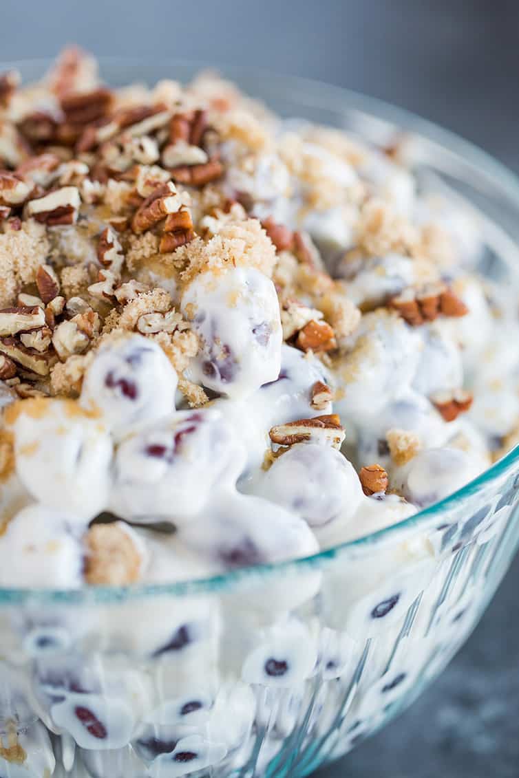 A bowl of grape salad topped with brown sugar and pecans.