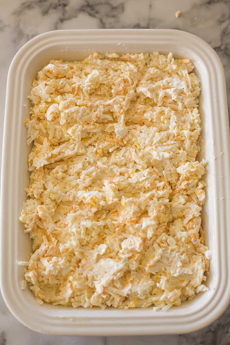 A pan of hashbrown casserole prepared and ready for the oven.