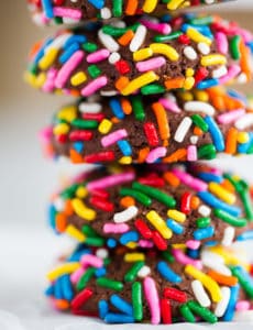 A stack of chocolate crinkle cookies rolled in sprinkles.