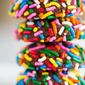 A stack of chocolate crinkle cookies rolled in sprinkles.