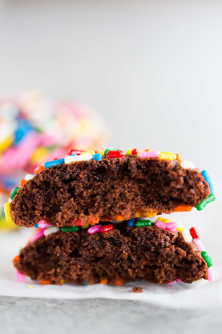 A chocolate crinkle sprinkle cookies broken in half and stacked.
