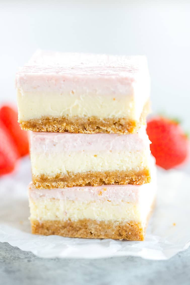 Three strawberry cheesecake bars stacked on top of one another.