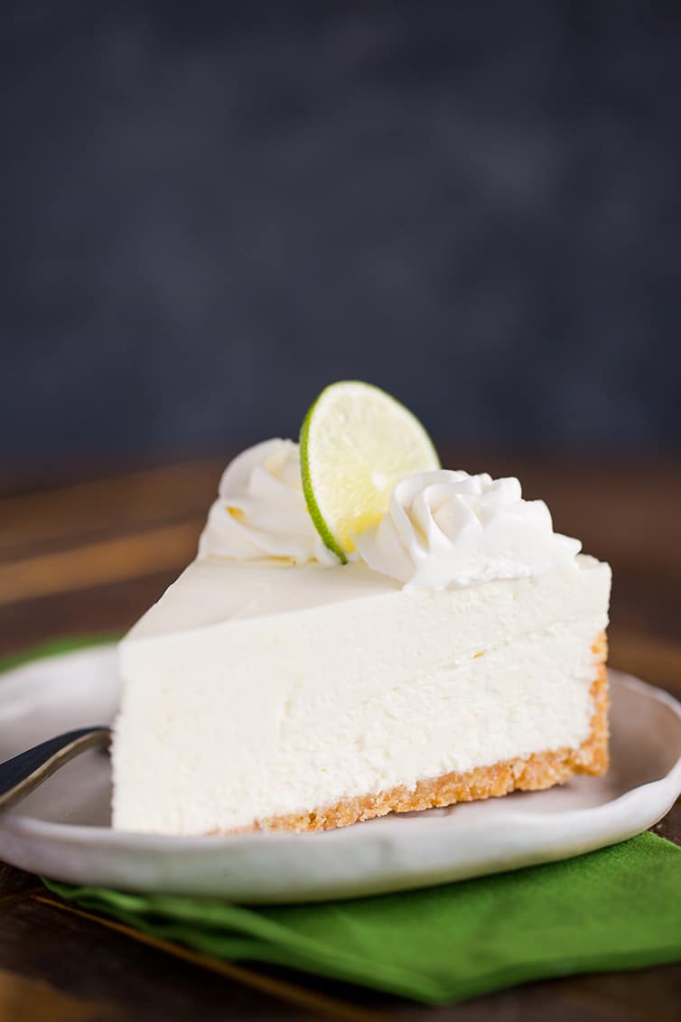 A slice of key lime cheesecake on a plate with a green napkin.