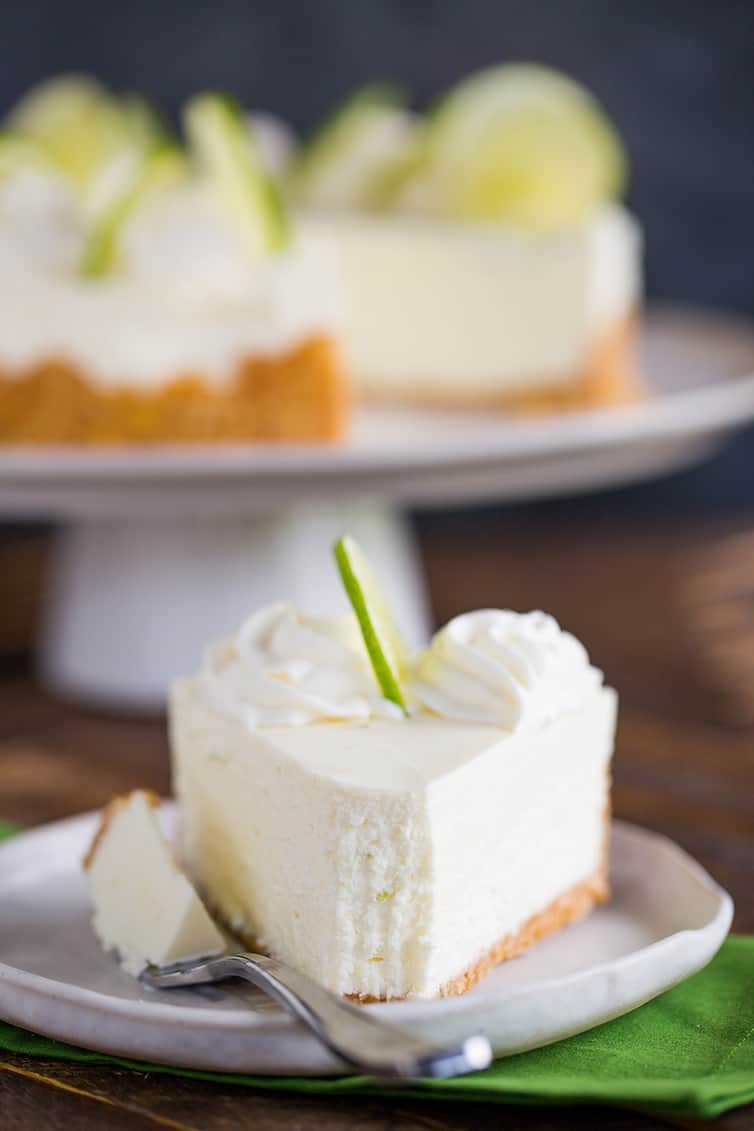 A slice of key lime cheesecake with a forkful taken out. 