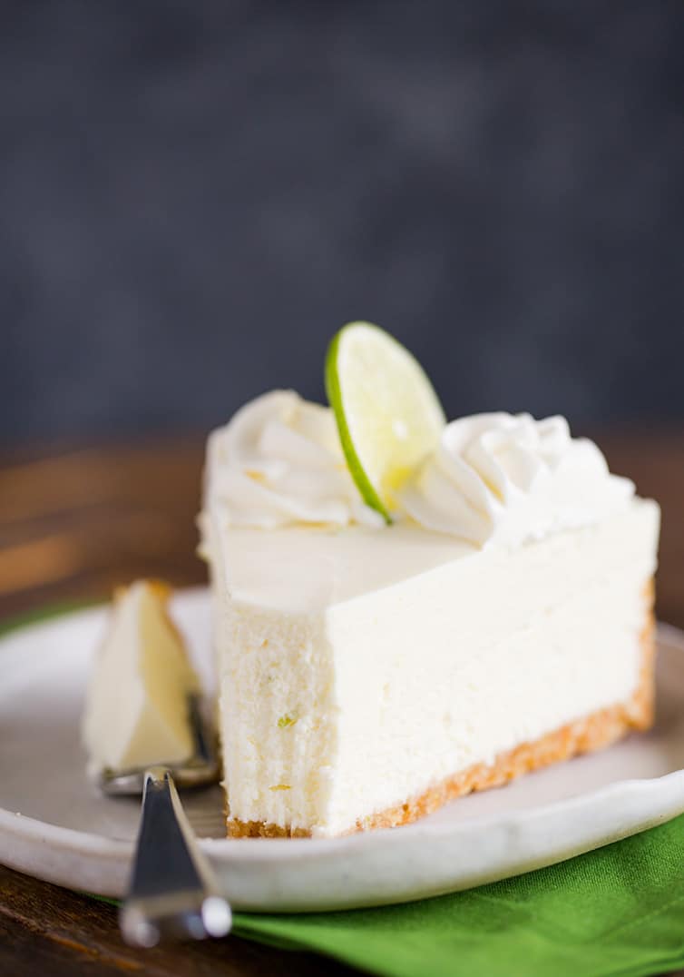 A slice of key lime cheesecake with a forkful taken out.