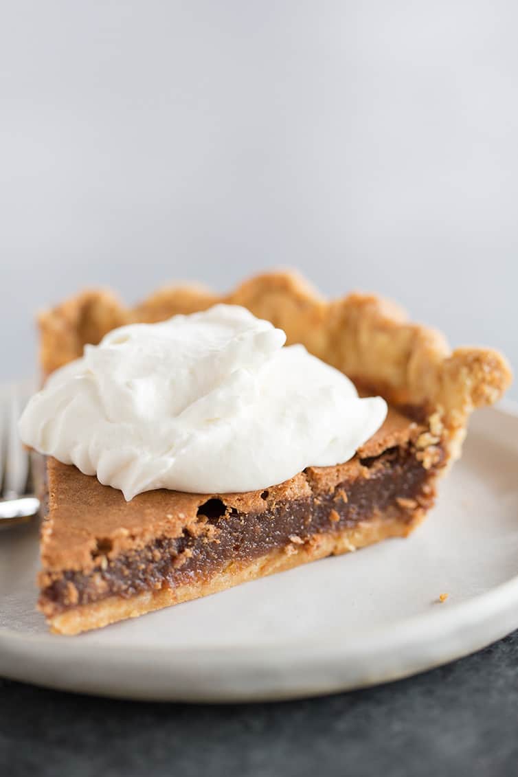 A slice of chocolate chess pie with whipped cream on top.